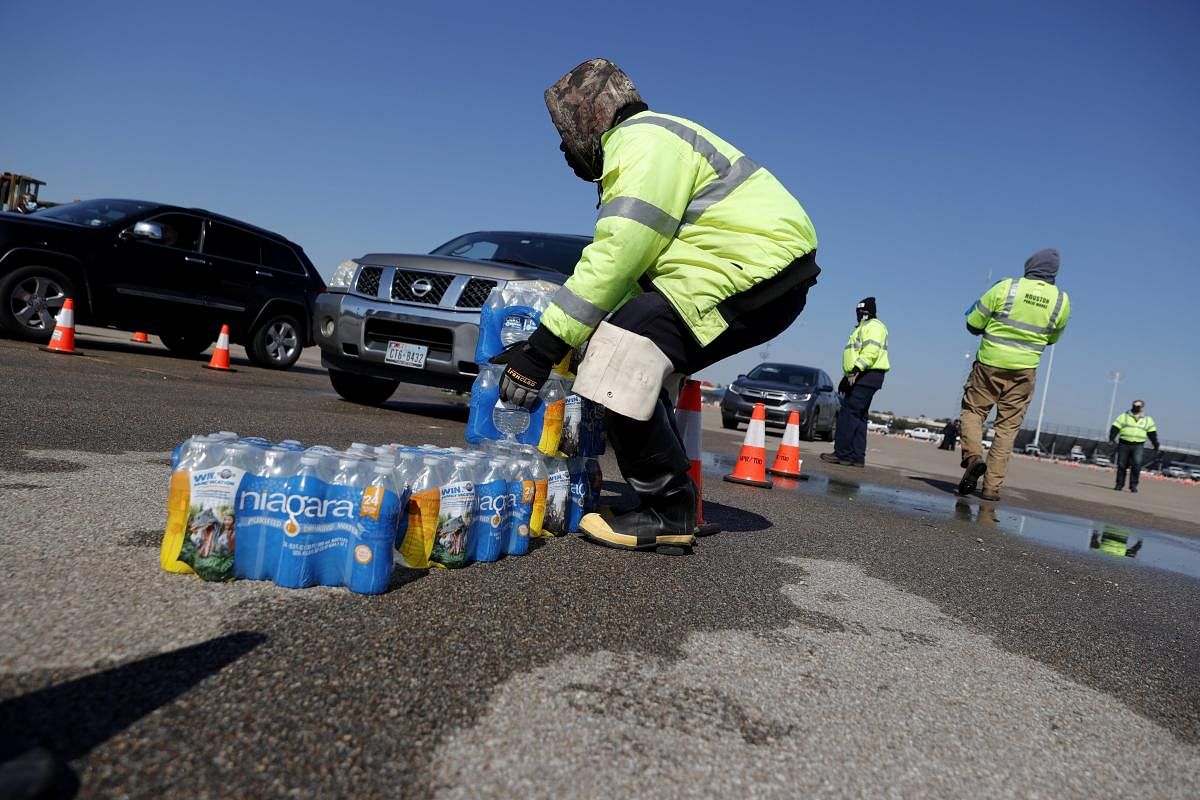 Workers with Houston Public Works prepare to load cases of water into waiting cars during a mass water distribution at Delmar Stadium on February 19, 2021 in Houston, Texas. Credit: AFP photo.