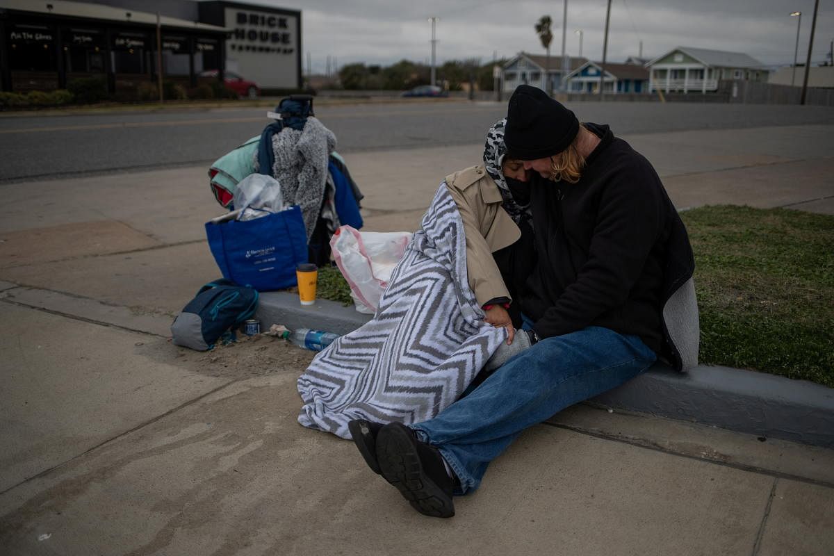 Couple Renne Alva, 37, and Travis Wasicek, 43, sit amongst their belongings along Seawall Boulevard as they embrace to keep each other warm. Credit: Reuters photo.