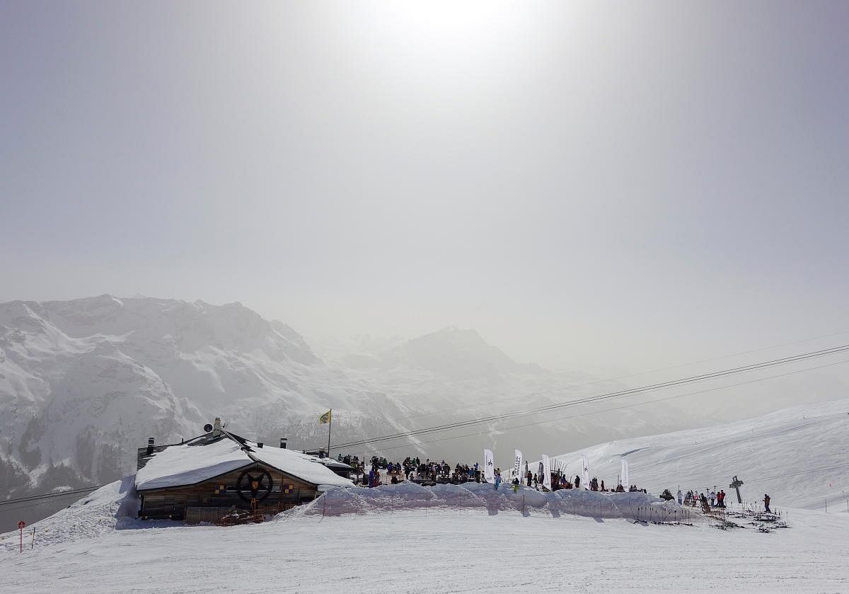 Sahara dust makes the sky misty as skiers rest on the terrace of a restaurant beside a piste at the Corviglia ski area, as the spread of the coronavirus disease continues, in the Alpine resort of St. Moritz, Switzerland. Credit: Reuters photo.