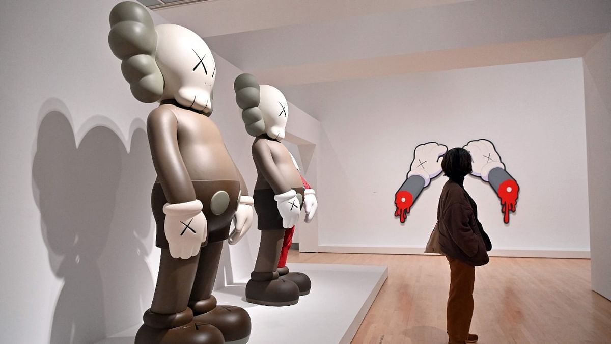 A person looks at art work by American artist and designer KAWS, whose real name is Brian Donnelly, during a preview of the exhibit