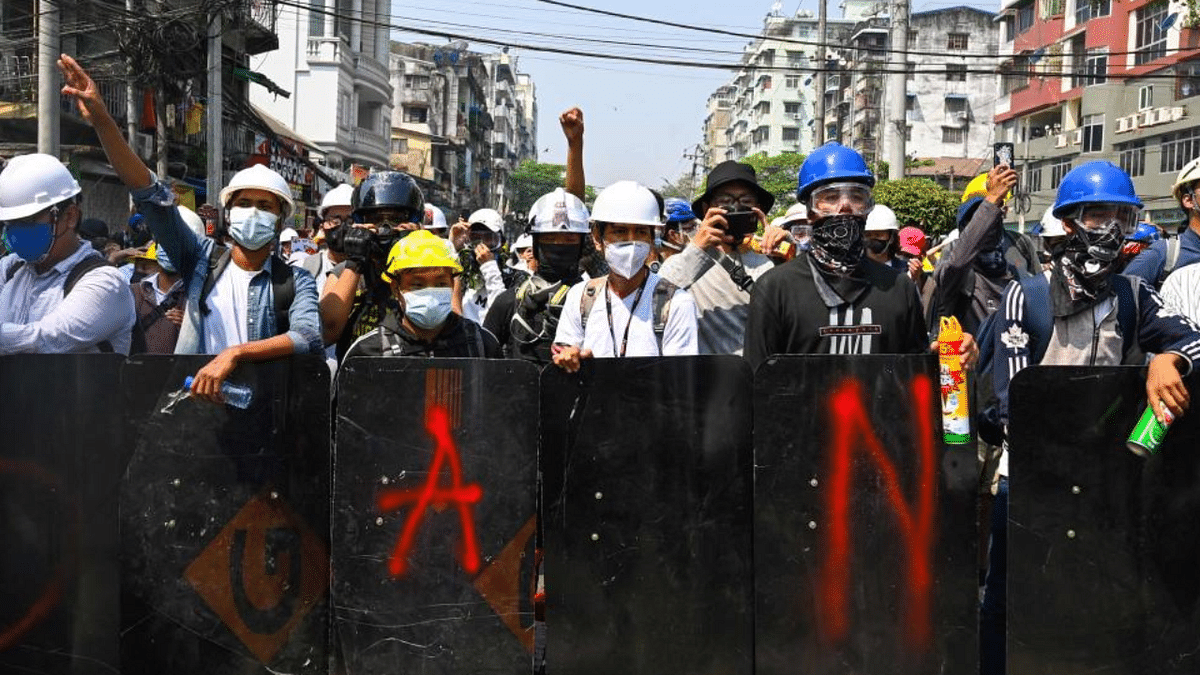 Protesters stand behind makeshift shields during a demonstration against the military coup in Yangon. Credit: AFP Photo