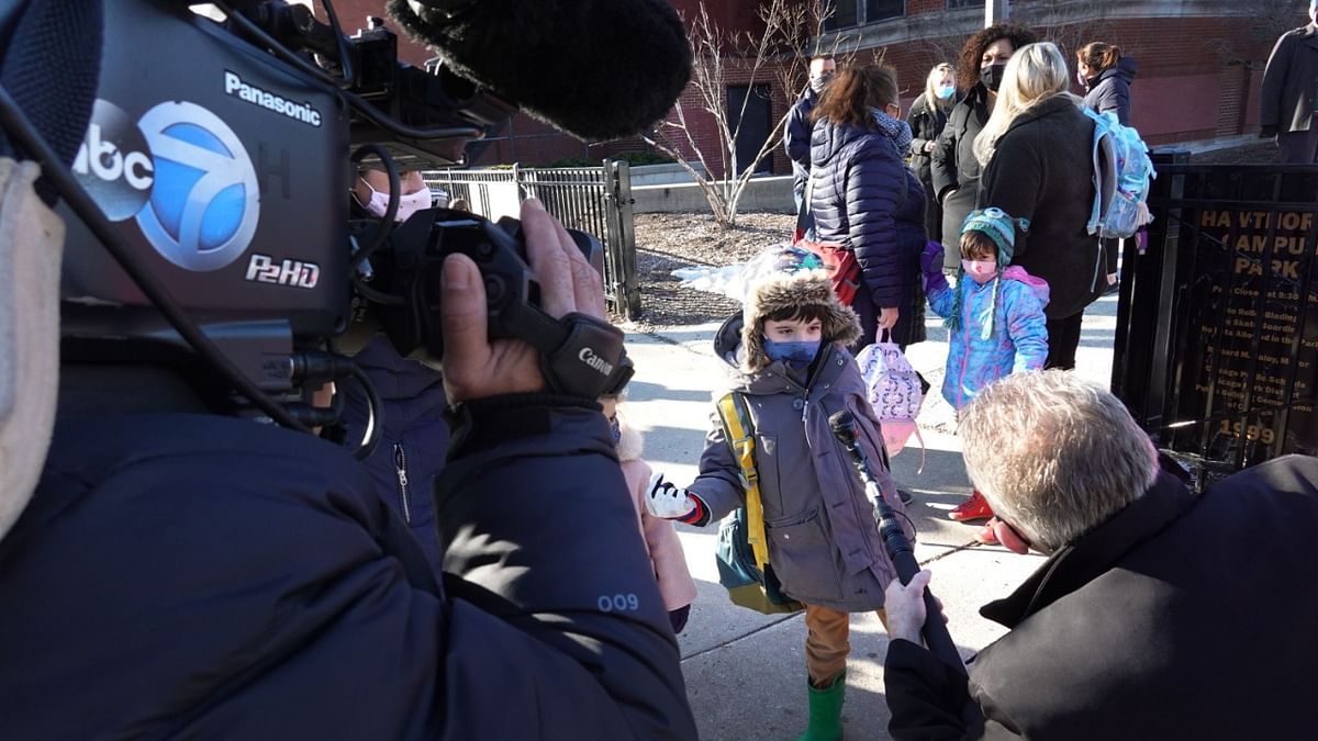 Children are interviewed by a television news reporter as they leave Hawthorne Scholastic Academy following their first day of in-person learning in Chicago, Illinois. Credit: AFP Photo