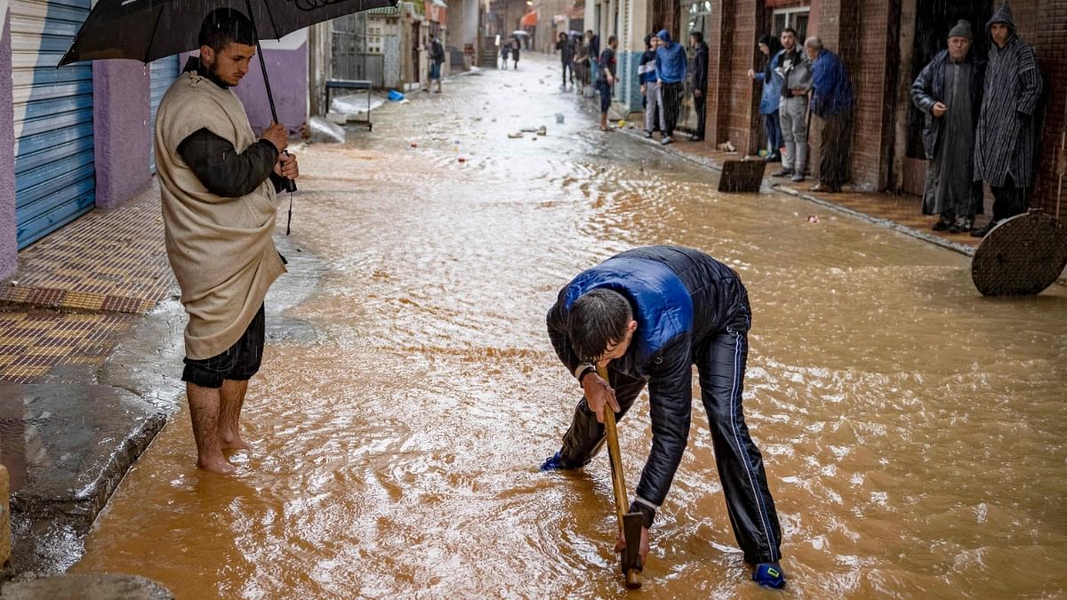 A young man tries to unblock a gutter on a flooded street during stormy weather in the northern Moroccan town of Fnideq. Credit: AFP Photo