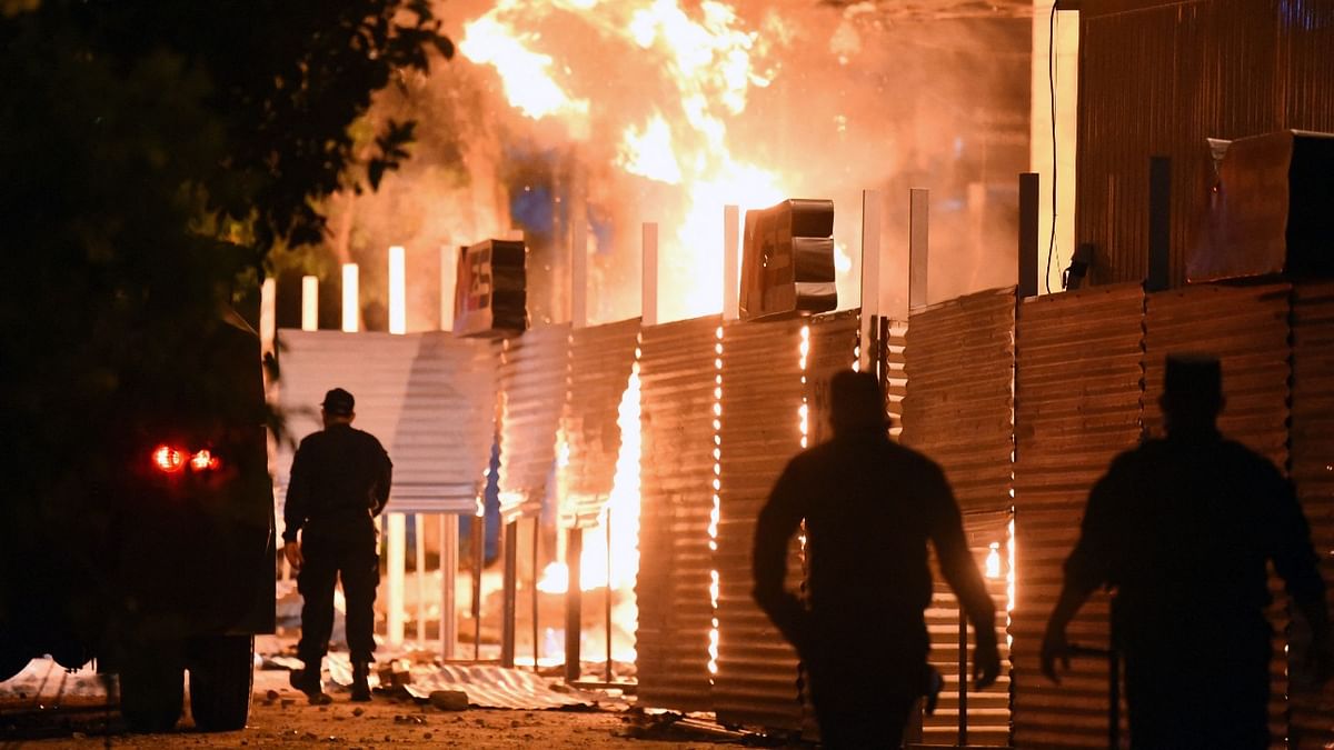 Policemen are seen near a fire set on by demonstrators at the Commerce Ministry headquarters during a protest against corruption and lacks in the health system, demanding the resignation of Paraguayan President Mario Abdo Benitez, in Asuncion. Credit: AFP Photo