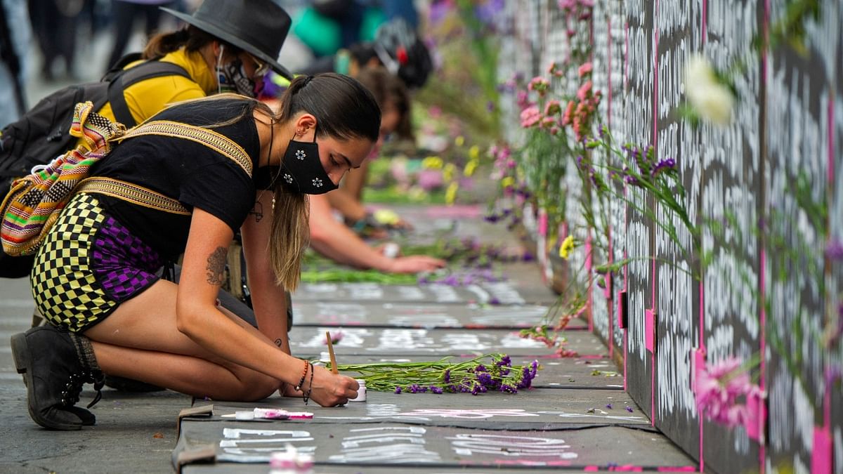 A woman writes on the pavement next to a metal fence with the names of other victims surrounding the National Palace ahead of the International Women's Day, in Mexico City. Credit: AFP Photo
