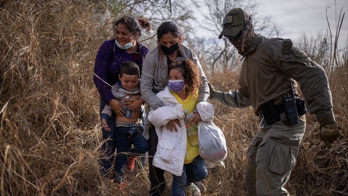 Asylum seeking migrants weep as they are escorted out of think brush by a Texas State Trooper after they crossed the Rio Grande river into the United States from Mexico on a raft in Penitas, Texas. Credit: Reuters Photo.