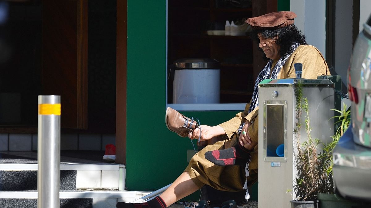 Al Noor mosque shooting survivor Taj Mohammed Kamran takes off his shoes before entering the mosque in Christchurch ahead of a memorial service to mark two years since the Christchurch mosque mass shootings. Credit: AFP Photo