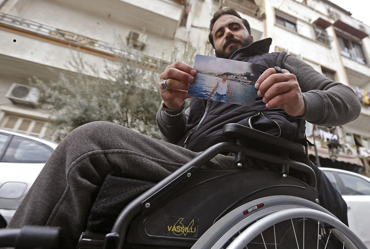 In the capital Damascus, 33-year-old Samer Sawwan holds up a picture of himself standing on a beach in the coastal resort of Latakia.  That was before a bullet shot through his car while he was driving in 2011, sending the vehicle into a barrel roll that paralysed him forever.