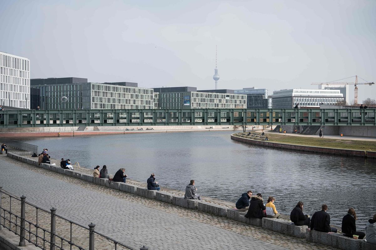 People sit on the bank of the river Spree under a clear blue sky in Berlin. Europe's biggest economy had begun easing restrictions, first reopening schools in late February, before allowing some shops to resume business in March. Germany was widely praised for its handling of the first wave of the pandemic, but has struggled to contain new infections since they began spiralling out of control in a second wave late last year. Credit: AFP Photo