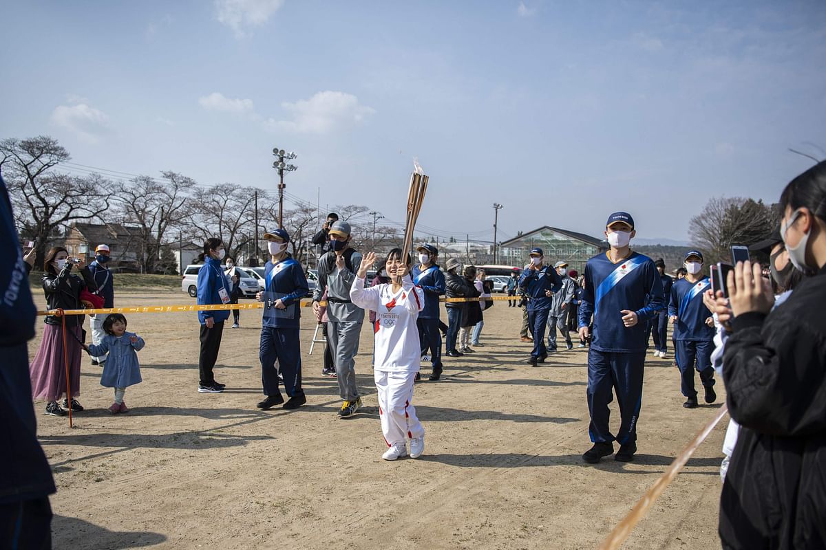 Torchbearer Rio Suzuki (C), a junior high school student, carries the Olympic torch after the start of the second day of the Tokyo 2020 Olympic Games torch relay at Somanakamura Shrine in the town of Soma, Fukushima Prefecture. Credit: AFP Photo