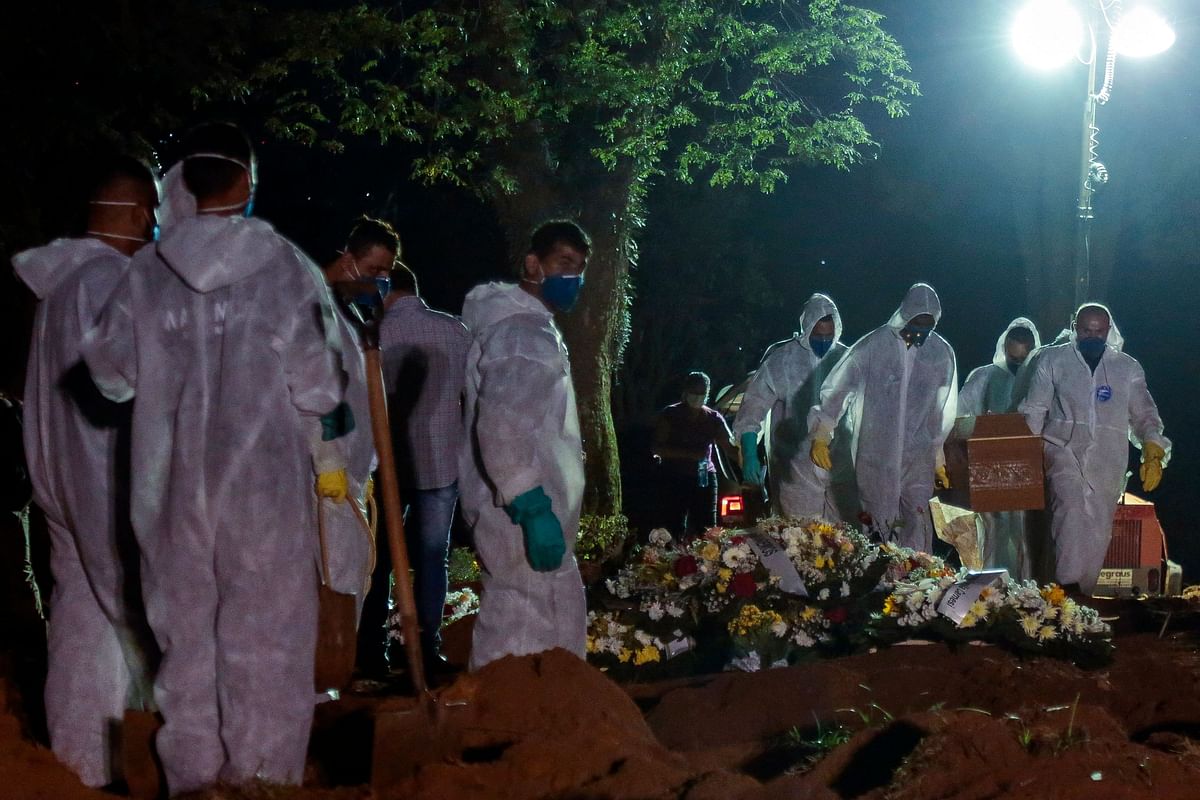 Cemetery workers carry a coffin during the first burial at night amid the Covid-19 pandemic at the Vila Formosa cemetery in Sao Paulo, Brazil. Brazil surpassed 100,000 new Covid-19 cases in one day on Thursday, adding another grim record in country where the pandemic has killed more than 300,000 people. Credit: AFP Photo