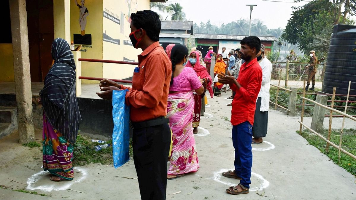 Voters queue up, maintaining social distance as precaution against Covid-19, outside a polling station during the first phase of polling for Assam Assembly elections, at Rupohi in Nagaon district. Credit: PTI Photo