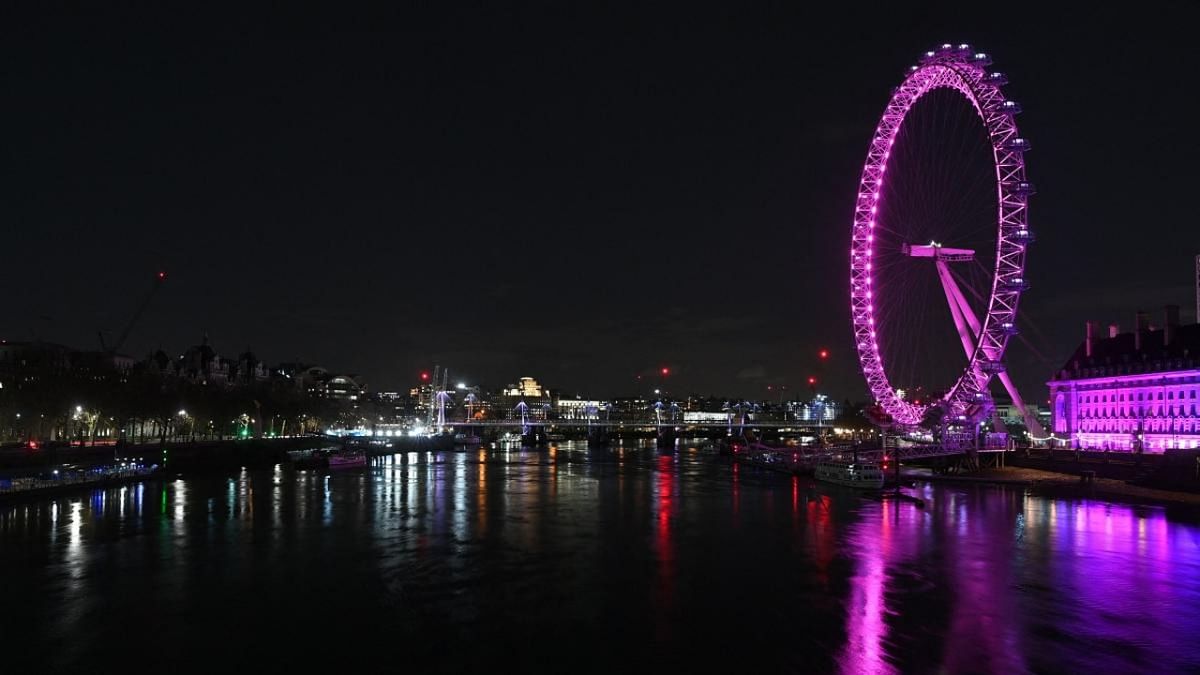 A picture taken on March 27, 2021 in central London shows London landmark The London Eye before being submerged into darkness for the Earth Hour environmental campaign. Credit: AFP.