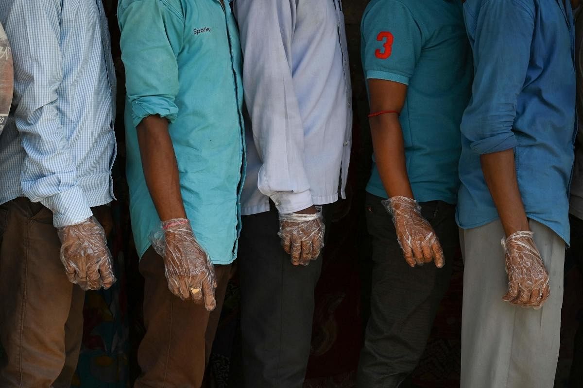 Voters wearing plastic gloves stand in a line to cast their vote outside a polling station during Phase 2 of West Bengal's legislative election in Nandigram. Credit: AFP Photo