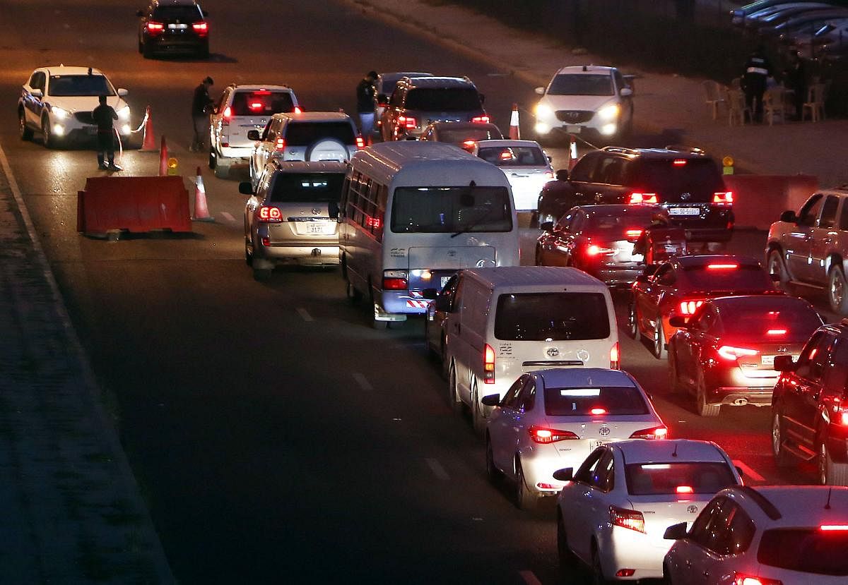 Kuwaiti policemen control cars at a check point set up on Fourth Ring road, during a curfue imposed by the authorities in abid to stem the spread of the coronavirus, in the capital Kuwait City. Credit: AFP photo.