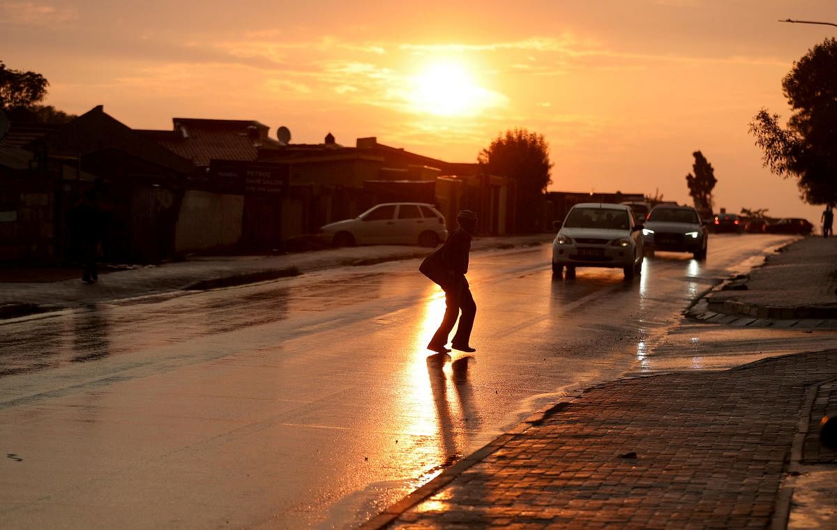 A person crosses the street during sunset, amid the coronavirus disease in Soweto, South Africa. Credit: Reuters photo.