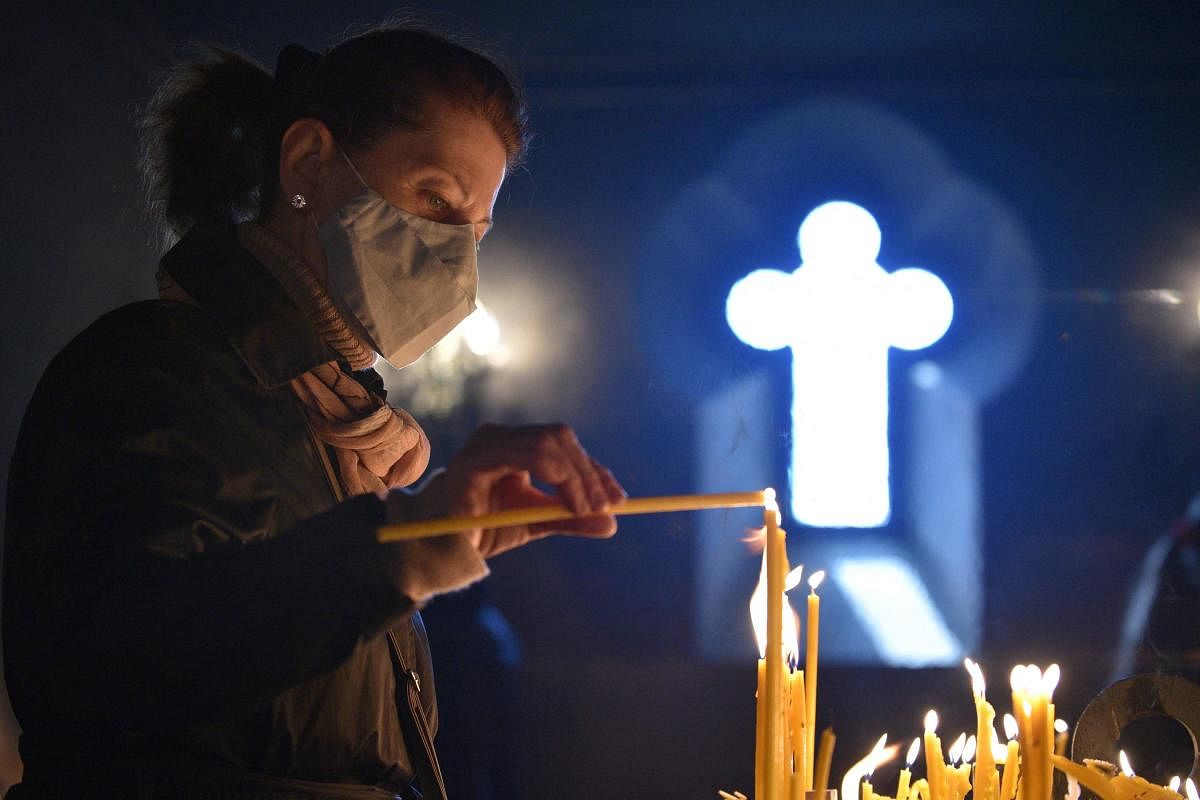 An Armenian Christian worshipper lights candles during an Easter religious service in Yerevan on April 4, 2021. | AFP Photo