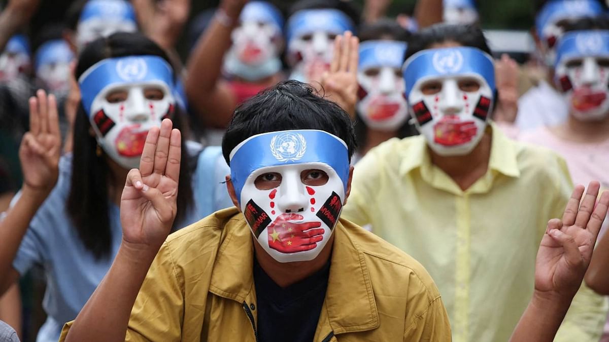 Protesters make the three-finger salute while wearing masks that express what they say is Chinese interference in the UN's handling of Myanmar affairs after the military coup in Yangon's Kamayut township. Credit: AFP Photo/Burma Associated Press