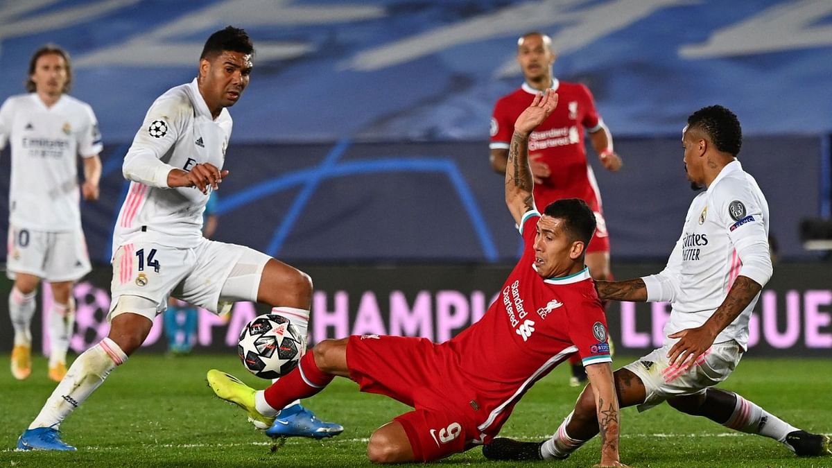 Liverpool's Brazilian midfielder Roberto Firmino (C) challenges Real Madrid's Brazilian midfielder Casemiro (L) and Real Madrid's Brazilian defender Eder Militao during the UEFA Champions League first leg quarter-final football match between Real Madrid and Liverpool. Credit: AFP Photo