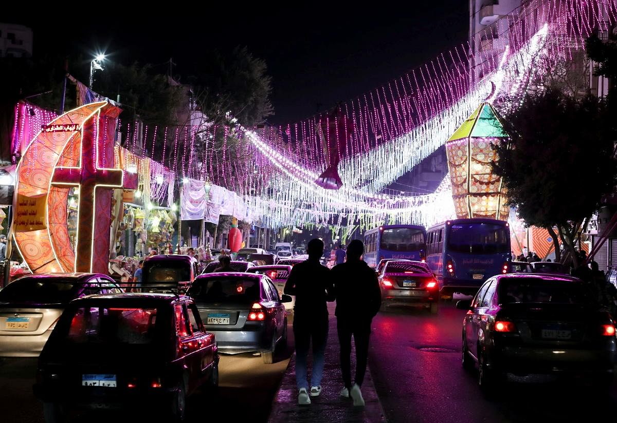People walk on the street past a shop stall with traditional Ramadan lanterns, called