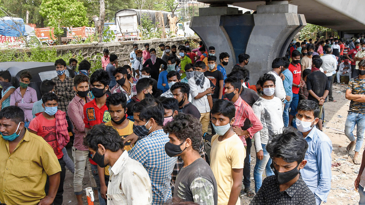 Migrant workers wait for bus along the Nashik highway to leave for their home states after surge in coronavirus cases, in Thane. Credit: PTI Photo
