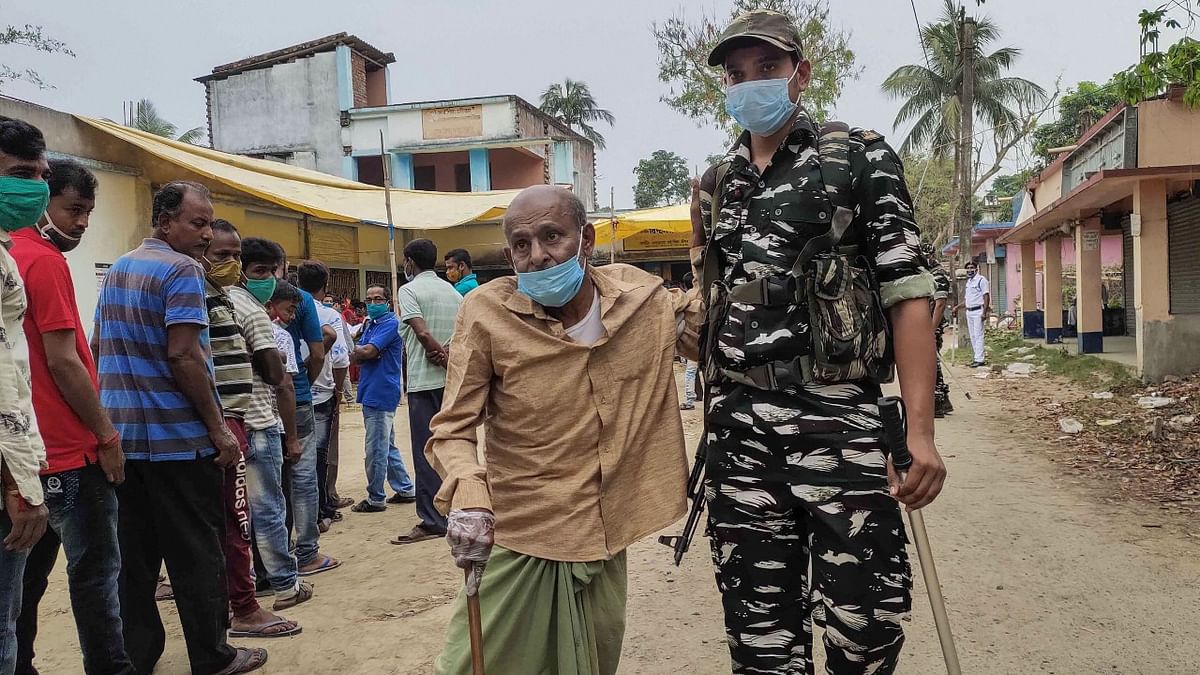Security personnel help an elderly voters after casting his votes at a polling station during the fourth phase of West Bengal Assembly elections, at Bangra Chakra village in South 24 Parganas district. Credit: PTI Photo