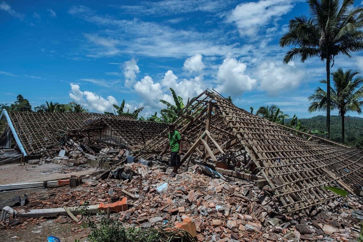 A man collects items from a damaged structure in Malang, East Java on April 11, 2021, a day after a 6.0-magnitude quake struck off the coast of Indonesia’s main Java island. Credit: AFP Photo