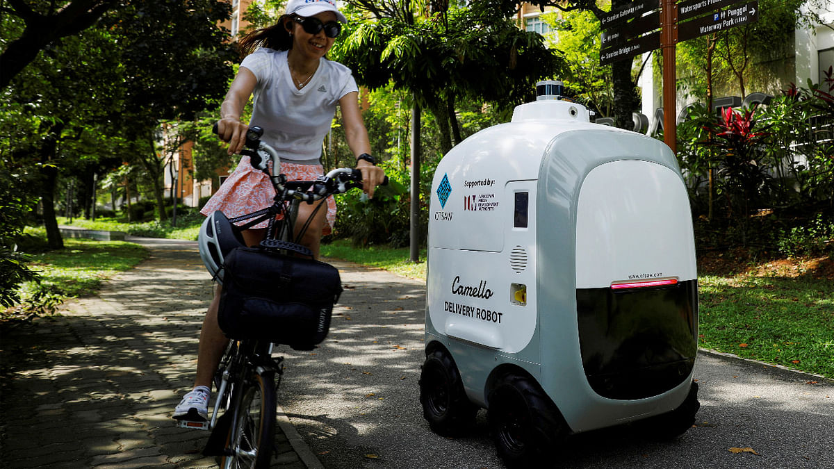 A cyclist passes as Camello, an autonomous grocery delivery robot, makes its way during a delivery in Singapore. Credit: Reuters Photo