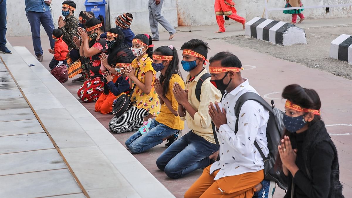 Pilgrims, wearing face masks, pray while on their way towards the cave shrine of Mata Vaishno Devi, during Navratri celebrations, in Reasi district, Tuesday, April 13, 2021.