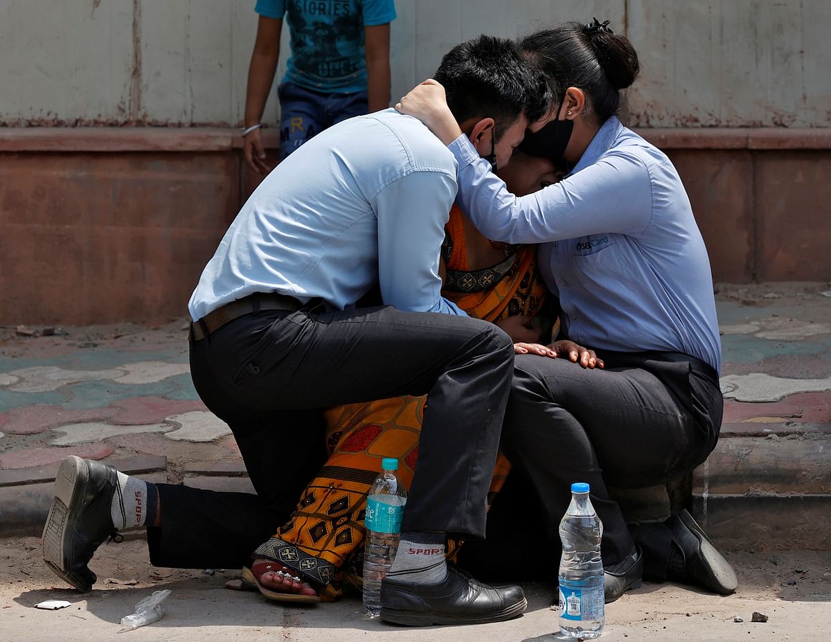 A woman is consoled by her children after her husband died due to the coronavirus disease (Covid-19) outside a mortuary of a Covid-19 hospital in New Delhi. Credit: Reuters photo