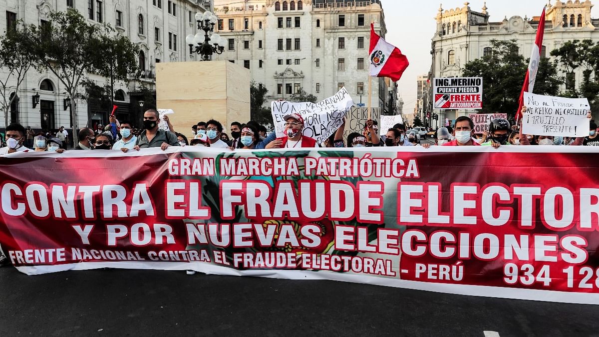 People march with a banner, signs and Peruvian national flags during a protest against Peru's presidential candidates Pedro Castillo and Keiko Fujimori, who will face each other in the second round of the presidential election, in Lima, Peru. Credit: Reuters photo