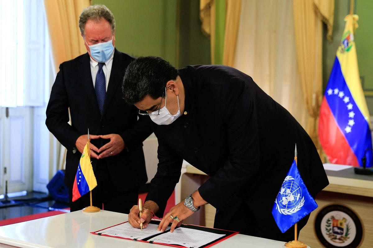 In this handout photo released by the Venezuelan presidency press office, Venezuelan President Nicolas Maduro (R) signs agreements during a meeting with the Executive Director of the United Nations World Food Program, David Beasley, at the Miraflores presidential palace in Caracas. Credit: AFP photo.