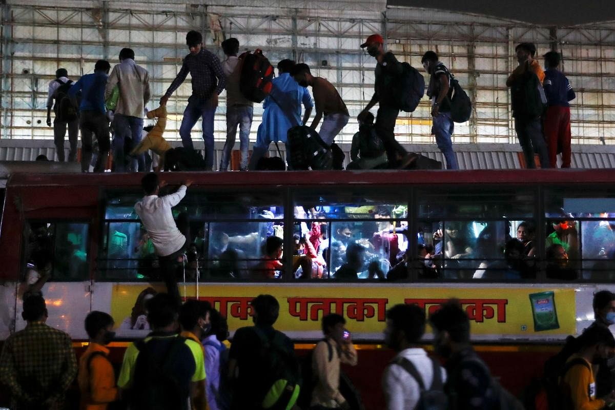 Migrant workers stand on top of an overcrowded bus to return to their villages. Credit: Reuters Photo