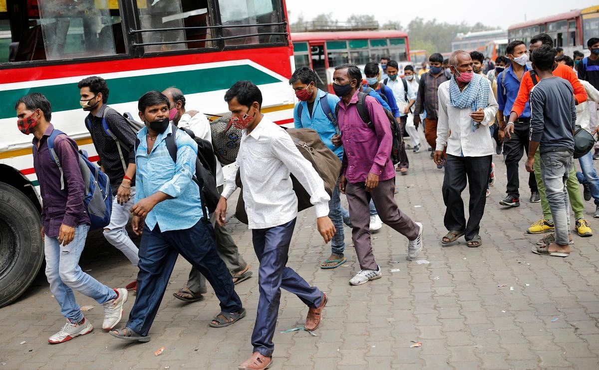 Migrant workers run after a moving bus to board, as they return to their villages, in Ghaziabad on the outskirts of New Delhi. Credit: Reuters Photo