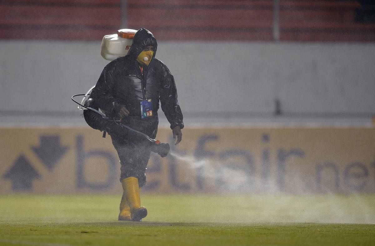 A worker disinfects the fiel before the Copa Sudamericana football tournament group stage match between Ecuador's Aucas and Brazil's Athletico Paranaense at the Gonzalo Pozo Stadium in Quito. Credit: AFP photo.