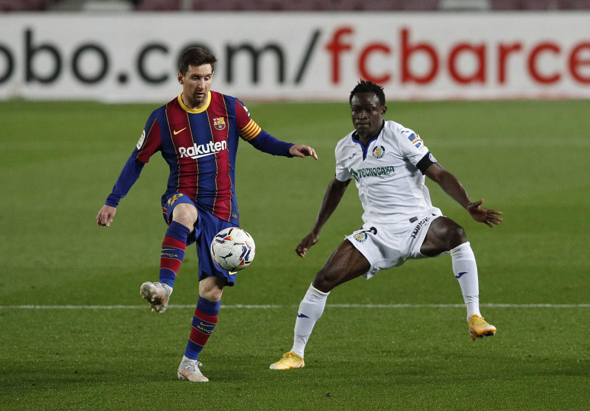Barcelona's Lionel Messi in action with Getafe's Djene Dakonam. Credit: Reuters photo.