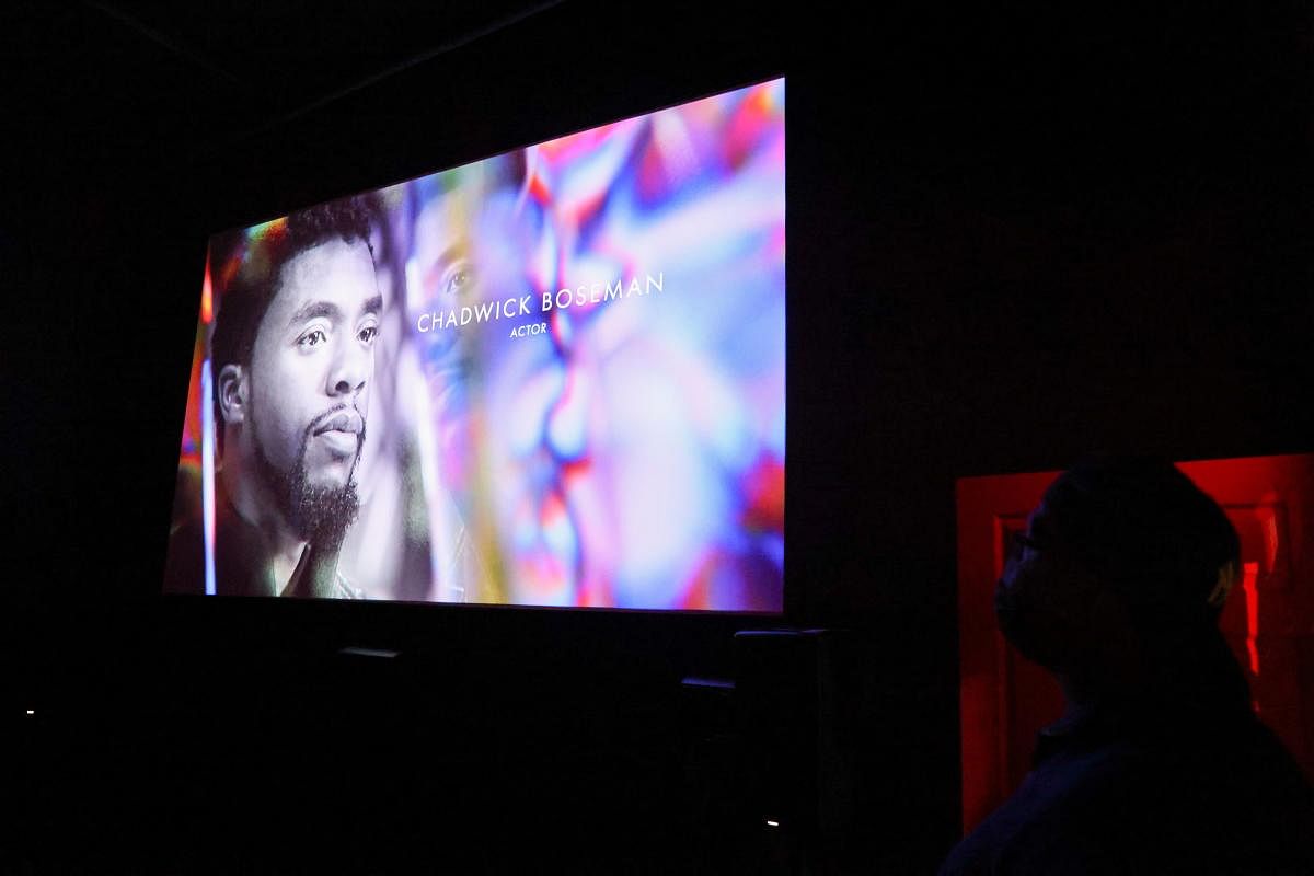 An audience member watches as Chadwick Boseman appears on screen during the annual In Memoriam presentation, at an Oscars watch party at the Stuart & Cinema Cafe, in Brooklyn. Credit: Reuters Photo