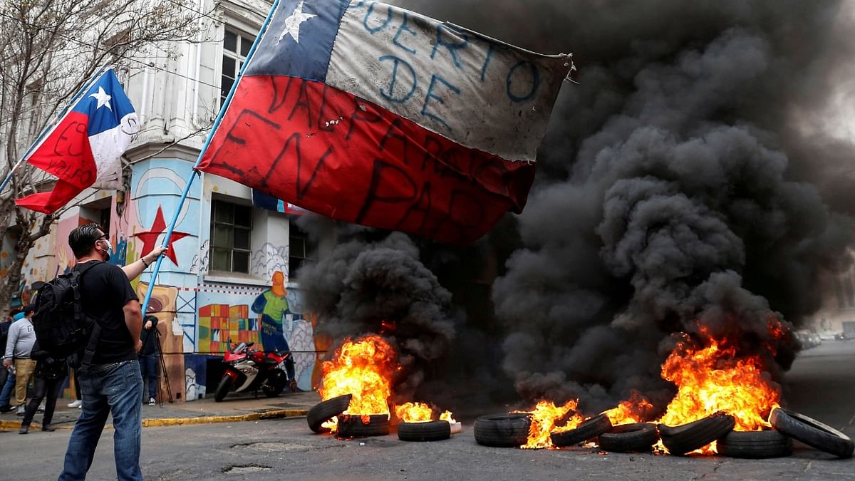 Tyres burn on a road as dockworkers protest against Chile's government seeking to block an approval made by lawmakers that would allow citizens to make another withdrawal from their privately-held pension savings to combat economic hardship generated by the coronavirus pandemic, in Valparaiso, Chile April 26, 2021. Credit: Reuters Photo