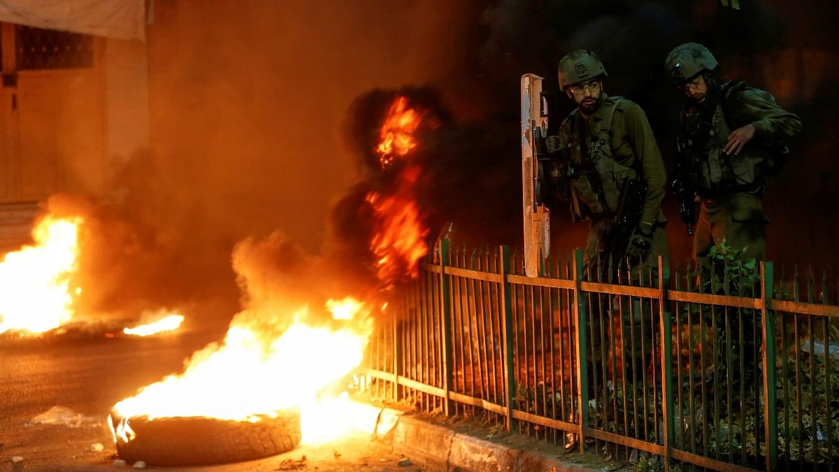Israeli soldiers stand next to burning tires as Palestinians take part in an anti-Israel protest over tension in Jerusalem, in Hebron in the Israeli-occupied West Bank. Credit: Reuters Photo