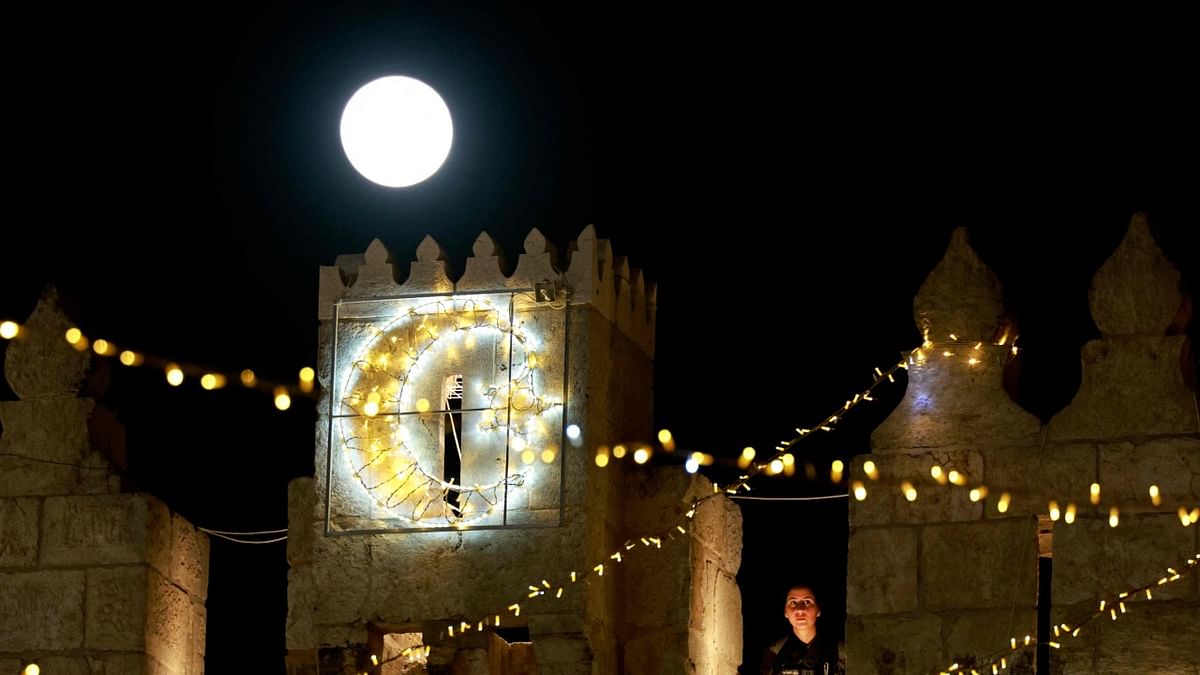 The Super Pink Moon, rises over the Damascus gate as an Israeli police stands guard in Jerusalem's Old City. Credit: AFP Photo