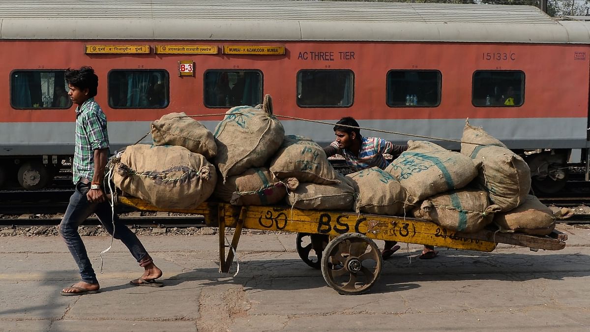 Labourers transport goods loaded on a handcart at a railway station in New Delhi.