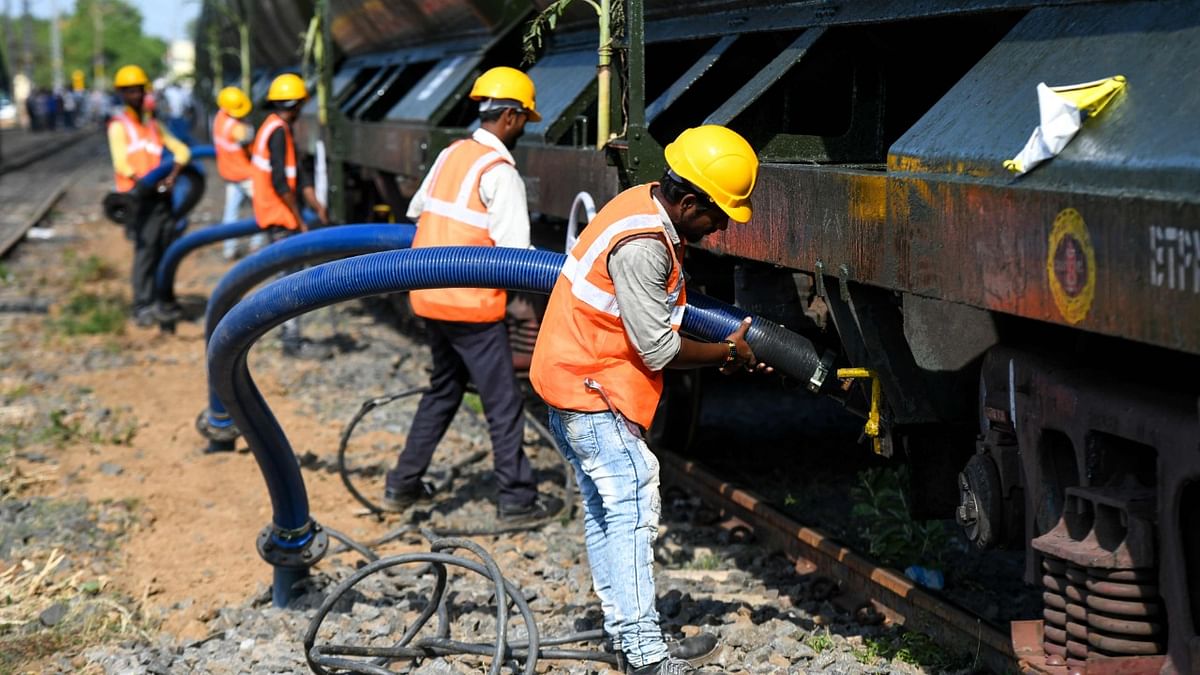 Labourers connect pipes to collect water from a special train at a railway station in Chennai.