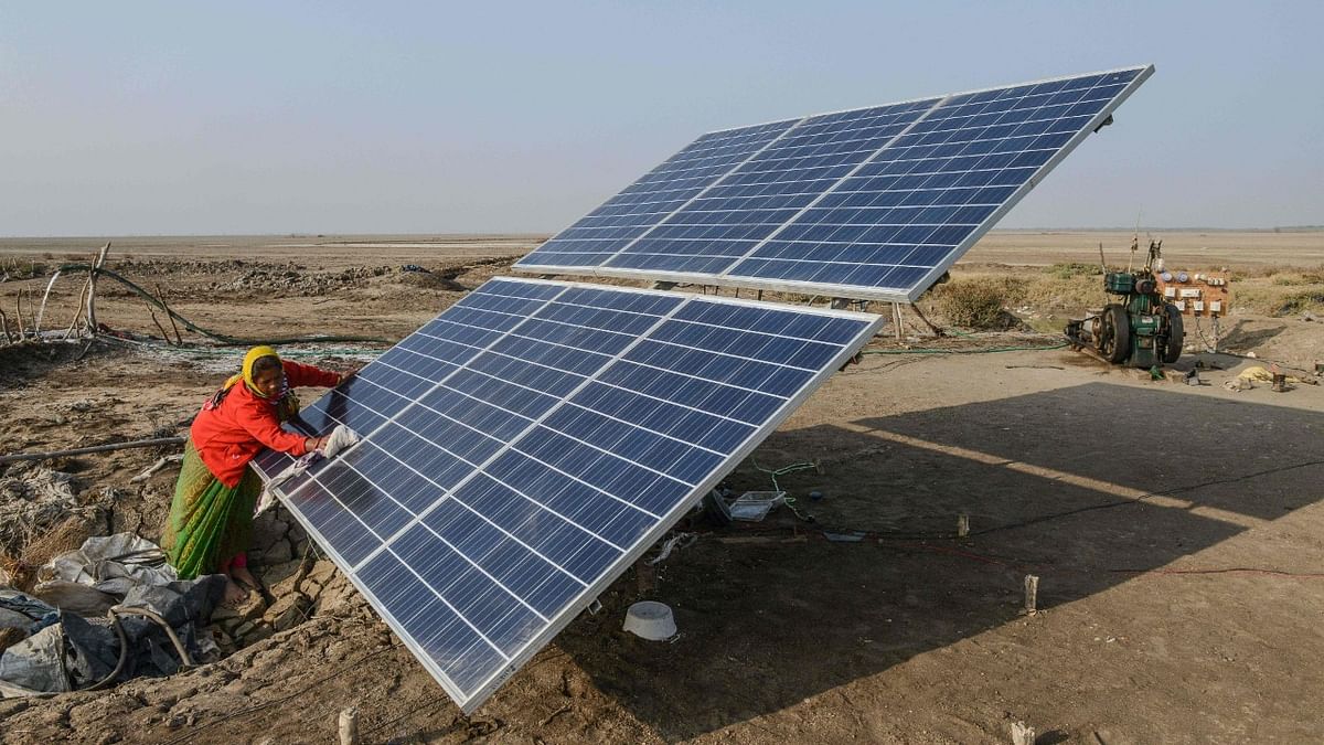 A labourer cleaning a solar panel used in deriving saline water, in the Little Rann of Kutch.