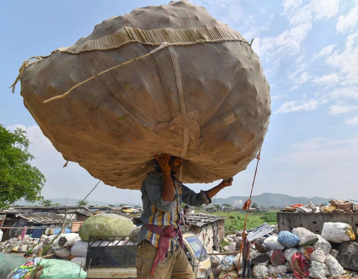 An Indian labourer carries a sack of plastic bottles on his head near one of the largest disposal sites in north-east India.