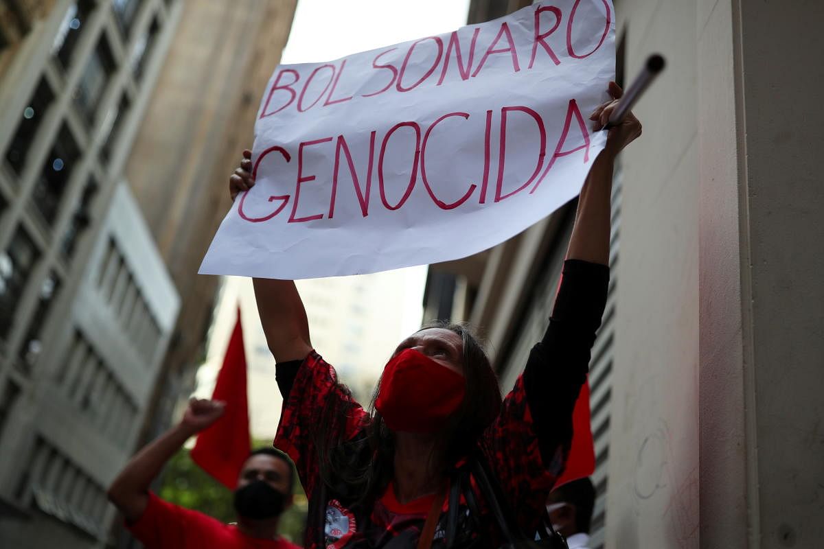 A demonstrator from the Roofless Workers Movement (MTST) holds a placard reading 'Bolsonaro genocidal' during a protest against Brazil's President Jair Bolsonaro and his handling of the coronavirus disease crisis, in Sao Paulo, Brazil. Credit: Reuters Photo