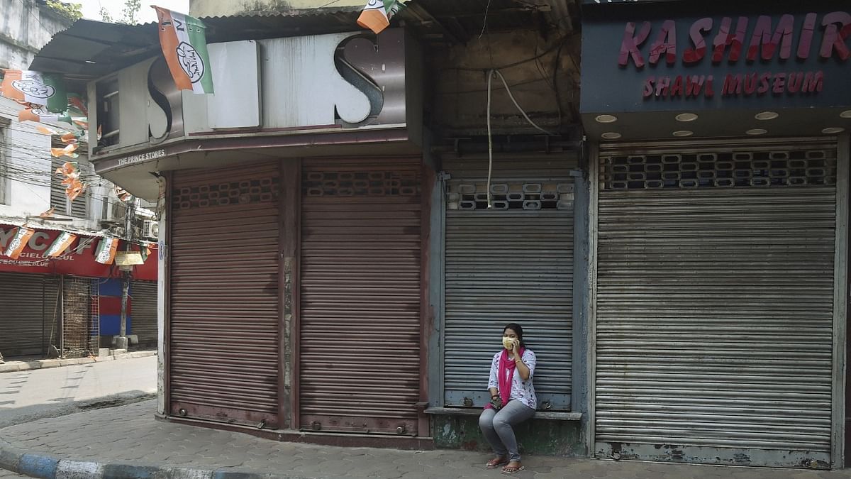 A lady sits outside a closed shop during a partial lockdown announced by the West Bengal Government to curb the spike in coronavirus cases, in Kolkata. Credit: PTI