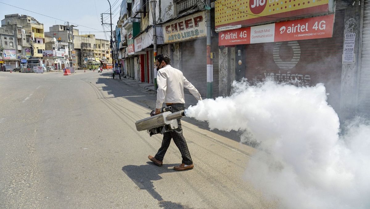 Municipal Corporation health worker sanitizes the closed market, as government orders weekend curfew in Jammu. Credit: PTI