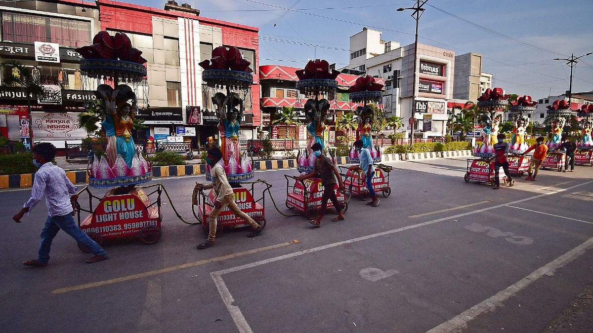 Workers pull decorative light trolleys used in wedding ceremonies along a partially deserted road as a weekend lockdown is in effect to curb the surge of Covid-19 coronavirus in Allahabad Credit: AFP