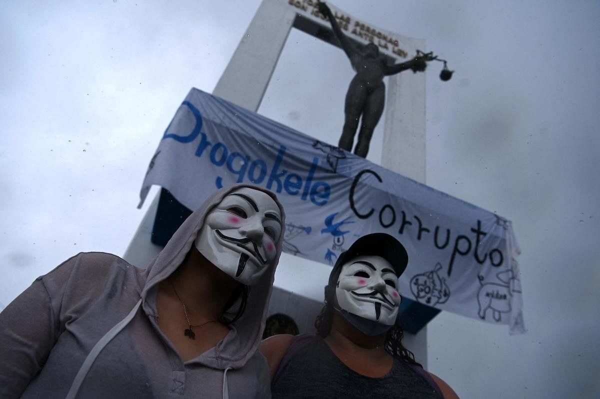 Men wear Guy Fawkes masks during a protest against the latest measures taken by the Legislative Assembly, including the dismissal of the Supreme Court judges and the Attorney General, in San Salvador, on May 2, 2021. Credit: AFP Photo