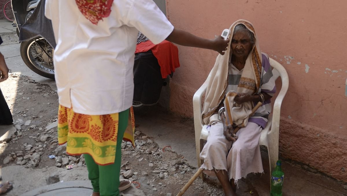 An elderly woman gets her temperature check done in Hyderabad.